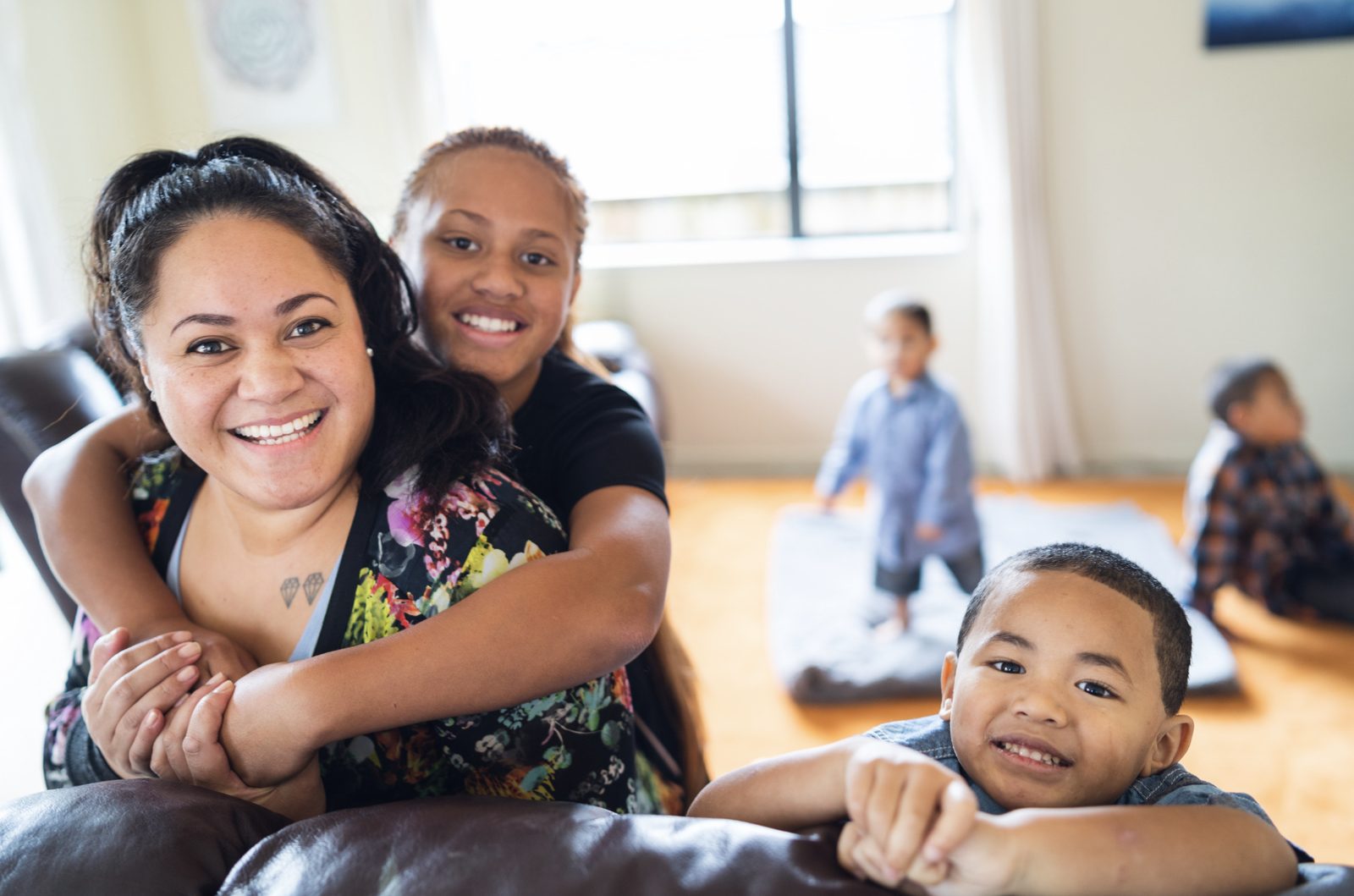 A mother laughing with her teenage daughter and young son at home